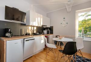 a kitchen with white cabinets and a table and chairs at Apartament z widokiem na morze u Grażyny 3 in Jarosławiec