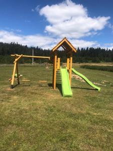 a playground with a green slide in a field at Apartmani Nišićka Oaza in Sarajevo