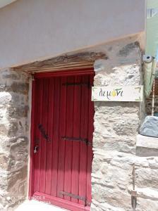 una puerta roja en el lateral de un edificio de piedra en Περιβόλι του Οδυσσέα, en Volissos