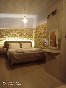 ein Schlafzimmer mit einem Bett mit einer Steinmauer in der Unterkunft Περιβόλι του Οδυσσέα in Volissos