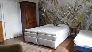 1 dormitorio con 2 camas y papel pintado con motivos florales en Château Le Tour - Chambres d'Hôtes, en Faux