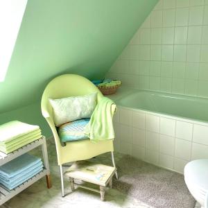 a bathroom with a chair next to a bath tub at Zauberhafte FeWo im Herzen von Wolfenbüttel in Wolfenbüttel