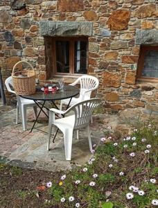 une table et des chaises assises devant un bâtiment en pierre dans l'établissement Charmante petite maison de pêcheur - Proche Ile de Bréhat et GR34, à Lézardrieux