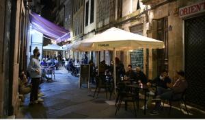 um grupo de pessoas sentadas em mesas sob um guarda-chuva em New J&J Hostel em Ourense