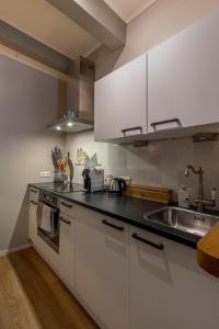 a kitchen with white cabinets and a sink at Sterlogies City Apartment Monsieur Philippe in Leeuwarden