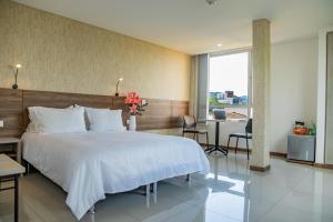 a bedroom with a large white bed and a desk at Hotel Estancia Chipichape Cali in Cali