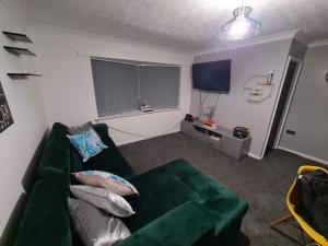 a living room with a green couch and a television at A Modern Lux 2 bedroom Apartment Near Alex Stadium & City WIFI FREE PARKING 15 - 30 Percent OFF - Longer STAYS 4 less Welcome in Birmingham