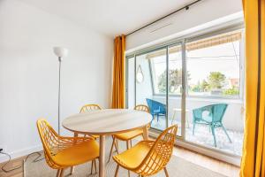 uma sala de jantar com uma mesa e cadeiras e uma janela em La Tortue Joyeuse - Appartement avec Loggia em Bernières-sur-Mer