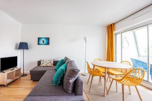 ein Wohnzimmer mit einem Sofa und einem Tisch in der Unterkunft La Tortue Joyeuse - Appartement avec Loggia in Bernières-sur-Mer