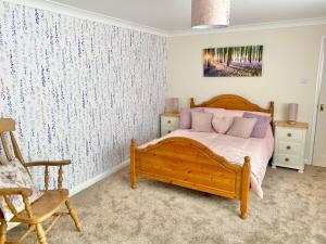 a bedroom with a wooden bed and a chair at Peaceful Country Cottage - views/walks - New 2022 in Lincoln