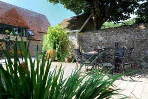 a patio with chairs and a table and a stone wall at The Forge in Rousdon