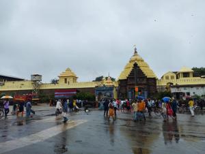 Un groupe de personnes marchant autour d'un temple sous la pluie dans l'établissement Divine view - Ac room for 2 pax - Swarna Bhavan, à Purî