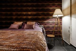 a bedroom with a bed and a striped wall at Lavendelhof luxe wellnesshouse in Zottegem +17 photos