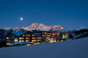 ein großes Gebäude im Schnee bei Nacht mit dem Mond in der Unterkunft Hotel Annapurna in Courchevel