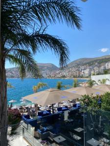 a view of a body of water with tables and umbrellas at Demi Hotel in Sarandë