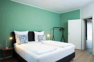 - une chambre avec un grand lit blanc aux murs bleus dans l'établissement Villa am Bahnhof in Fulda, à Fulde