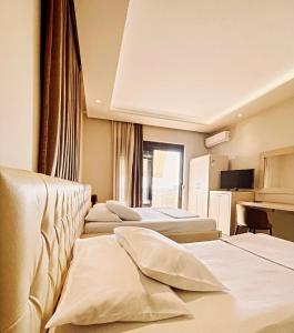 ein Hotelzimmer mit 4 Betten und einem Schreibtisch in der Unterkunft Hotel Lungomare in Vlorë