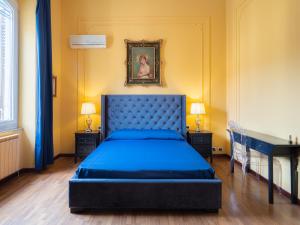 a bedroom with a blue bed and a painting on the wall at L'Opera Rooms & Suite in La Spezia