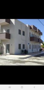 um grande edifício branco com um banco em frente em GEORGE & ELENA APARTMENTS em Amoudara Herakliou