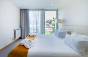 Un dormitorio con una gran cama blanca con una gran ventana. en Oca Vitoria Village, en Oporto 37 fotos más