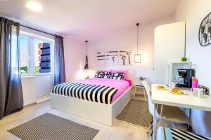 um quarto rosa e branco com uma cama e uma secretária em Le Petit 2 em Čilipi