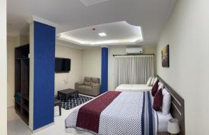 ein Schlafzimmer mit einem Bett, einem Sofa und einem TV in der Unterkunft Hotel del Parque in Ciudad del Este