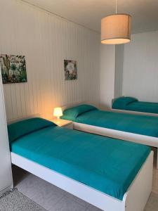 2 Betten in einem Schlafzimmer mit blauer Bettwäsche und einer Lampe in der Unterkunft Casa Nonna Delfina in Tortolì