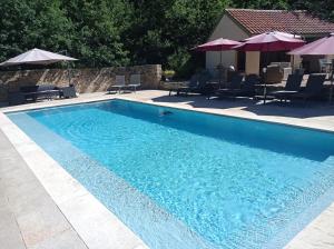 une grande piscine bleue avec des chaises et des parasols dans l'établissement La Roussilhe, à Sousceyrac