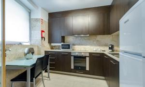 cocina con armarios de madera, mesa y nevera en Oca Vitoria Village, en Oporto