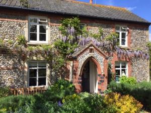 a brick house with a door and flowers on it at Stone Cottage in Thornage