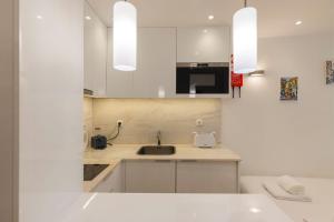 - une cuisine blanche avec évier et four micro-ondes dans l'établissement Alfama's Heart Studio by LovelyStay, à Lisbonne