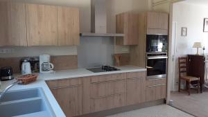 a kitchen with wooden cabinets and a stove top oven at Le gîte des Couderches in Plazac