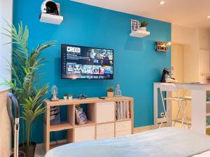 uma sala de estar com televisão numa parede azul em ☆ Les pieds sur terre ☆ tout confort ☆ NETFLIX ☆ em Metz