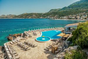 een resort met een zwembad en stoelen en de oceaan bij Ruza Vjetrova - Wind Rose Hotel Resort in Dobra Voda