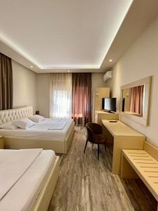 a hotel room with two beds and a desk at Hotel Lungomare in Vlorë