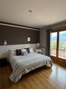a bedroom with a large bed and a large window at Hostal Pedraforca in Saldés