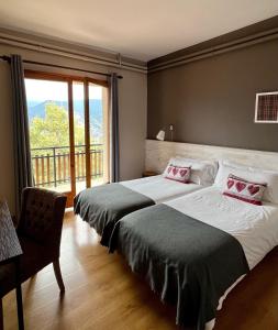 1 dormitorio con 2 camas y ventana grande en Hostal Pedraforca, en Saldes