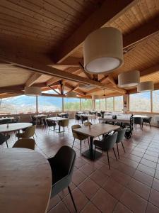 una sala da pranzo con tavoli, sedie e finestre di Hostal Pedraforca a Saldes