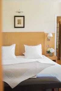 a bed with white sheets and pillows in a bedroom at Hostellerie De Levernois in Levernois