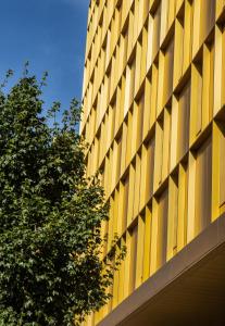 un bâtiment jaune avec un arbre devant lui dans l'établissement Crowne Plaza - Nice - Grand Arenas, an IHG Hotel, à Nice