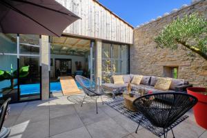 a patio with a couch and a table and chairs at Loft Industriel privé climatisé Piscine intérieure Terrasse SPA et jardin in Alzonne