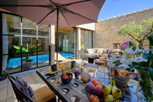 a table with food on it with an umbrella at Loft Industriel privé climatisé Piscine intérieure Terrasse SPA et jardin in Alzonne