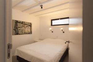 una camera da letto con un letto bianco e luci sul muro di Hof Aan Zee a Dishoek