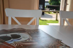 a table with a plate and two white chairs at Landhotel Rehedyk in Sankt Michaelisdonn