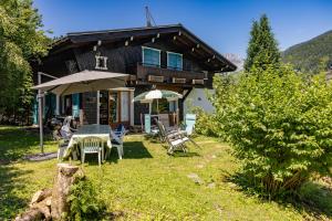 a house with a table and chairs and an umbrella at Chalet Le Margouillat in Les Houches