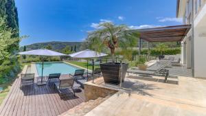 a pool with chairs and umbrellas next to a house at Villa Vista in Crestatx