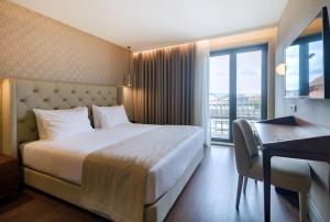 Cette chambre comprend un lit, un bureau et une fenêtre. dans l'établissement Oca Oriental Porto Hotel, à Porto