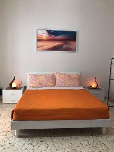 ein Schlafzimmer mit einem Bett mit orangefarbener Bettwäsche und zwei Lampen in der Unterkunft GIOELE'S HOME in Scafati