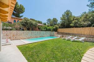 a backyard with a swimming pool and a lawn with lounge chairs at Villa Mar Clara By SunVillas Mallorca in Cala de Sant Vicent