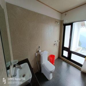 een badkamer met een toilet, een wastafel en een raam bij Istana Resort & Spa in Darjeeling